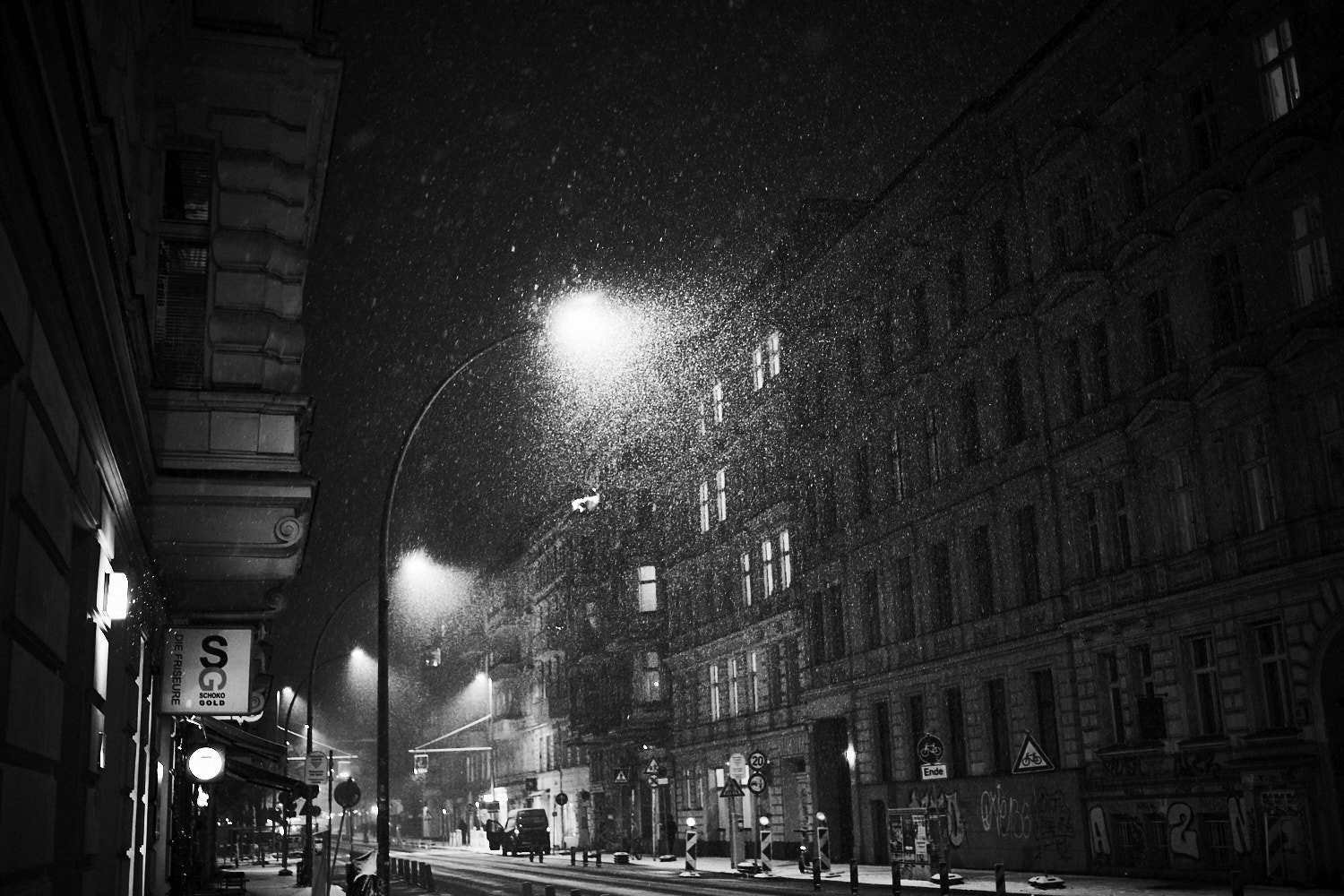  Schneefall in der Nacht über einer Berliner Straße in Schöneberg mit Straßenlaternen und Altbauten