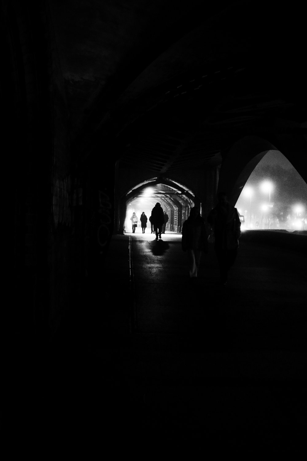 Silhouetted figures walking through an illuminated tunnel at Oberbaumbrücke in Berlin